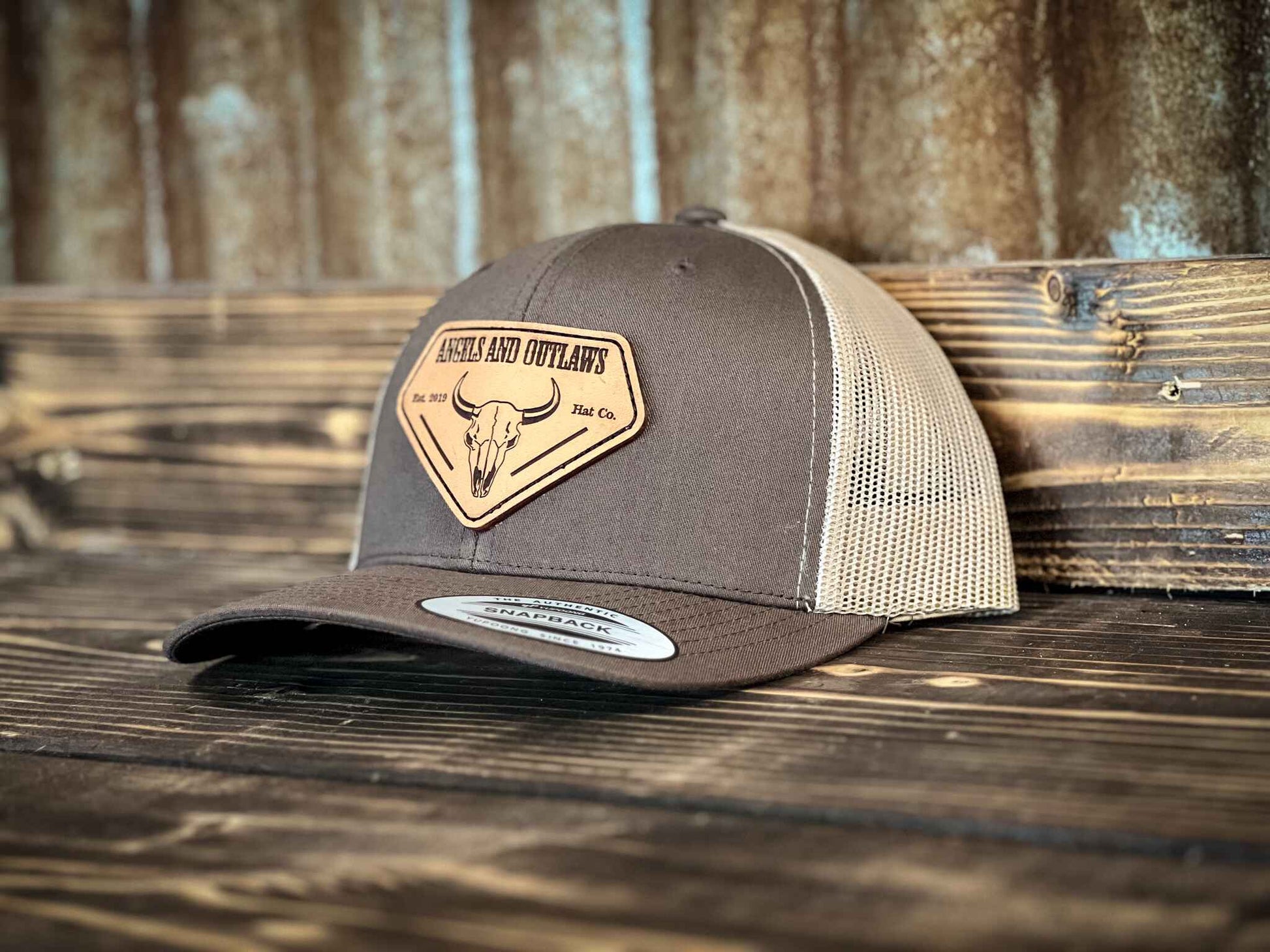Coffee front khaki back Mesh back trucker hat with Angels and Outlaws name and a bison skull engraved on a leather patch