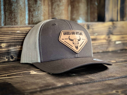 Coffee front Khaki back Mesh back trucker hat with Angels and Outlaws name and a bison skull engraved on a leather patch